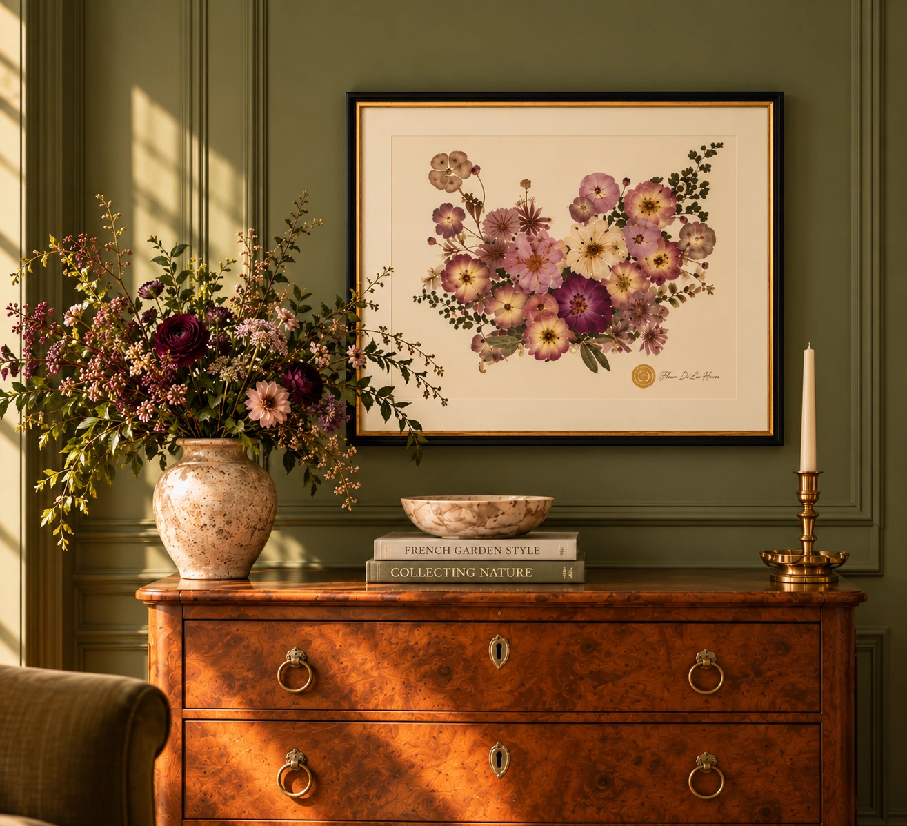 Signature pressed wedding bouquet artwork on an olive-green wall above a wooden dresser